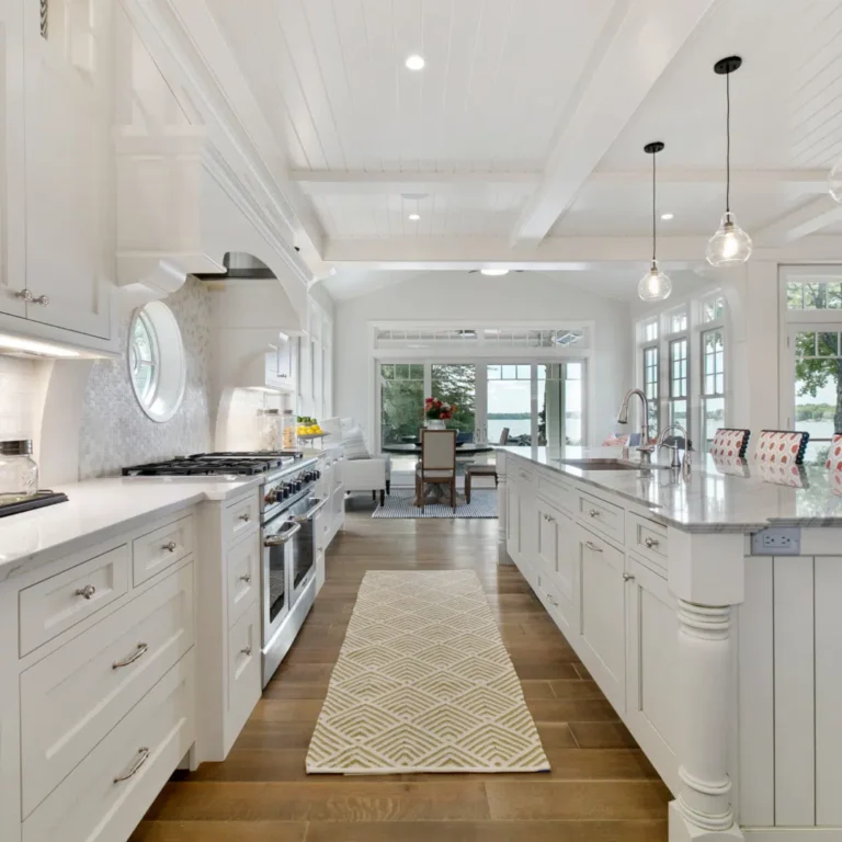 Bright white kitchen with cabinetry, an island and wood flooring, pictured on Premier's website